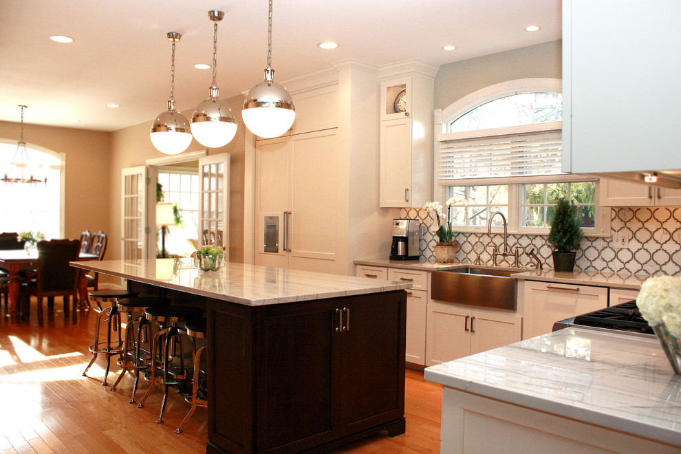 Modern inredning av ett mellanstort kök, med en rustik diskho, skåp i shakerstil, vita skåp, bänkskiva i kvartsit, vitt stänkskydd, stänkskydd i stenkakel, rostfria vitvaror, ljust trägolv och en köksö