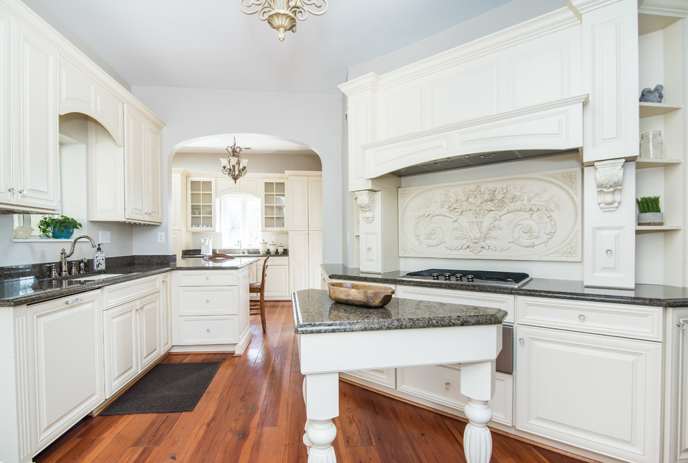 Exempel på ett stort klassiskt kök, med en undermonterad diskho, luckor med upphöjd panel, vita skåp, granitbänkskiva, vitt stänkskydd, rostfria vitvaror, mellanmörkt trägolv och en köksö