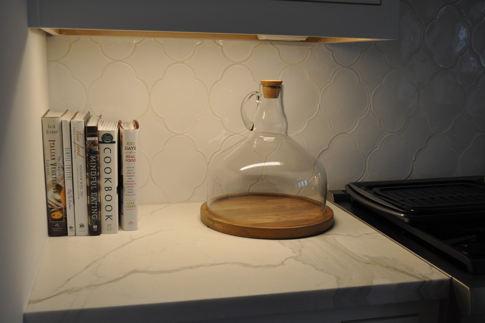 На фото: кухня в современном стиле с обеденным столом, мраморной столешницей и белым фартуком с