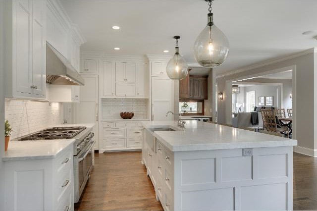 Idéer för ett stort klassiskt kök, med en rustik diskho, luckor med infälld panel, vita skåp, marmorbänkskiva, vitt stänkskydd, mellanmörkt trägolv och en köksö