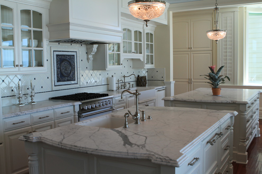 Eat-in kitchen - large traditional single-wall medium tone wood floor eat-in kitchen idea in Santa Barbara with an undermount sink, raised-panel cabinets, white cabinets, marble countertops, white backsplash, ceramic backsplash, stainless steel appliances and two islands