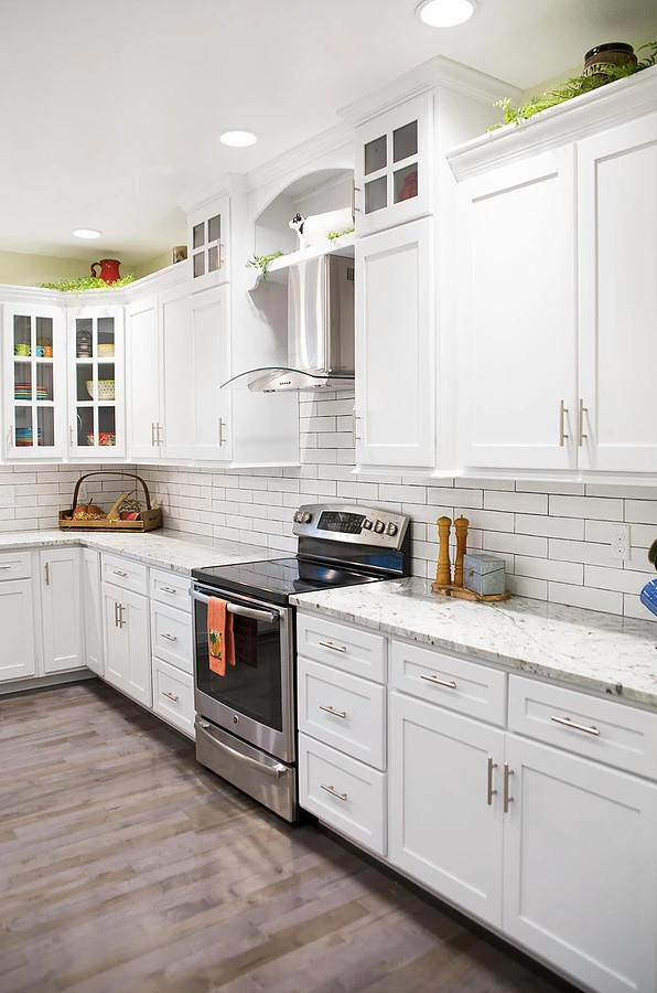Large farmhouse u-shaped medium tone wood floor and brown floor eat-in kitchen photo in Other with a farmhouse sink, shaker cabinets, white cabinets, quartzite countertops, white backsplash, subway tile backsplash, stainless steel appliances, an island and white countertops
