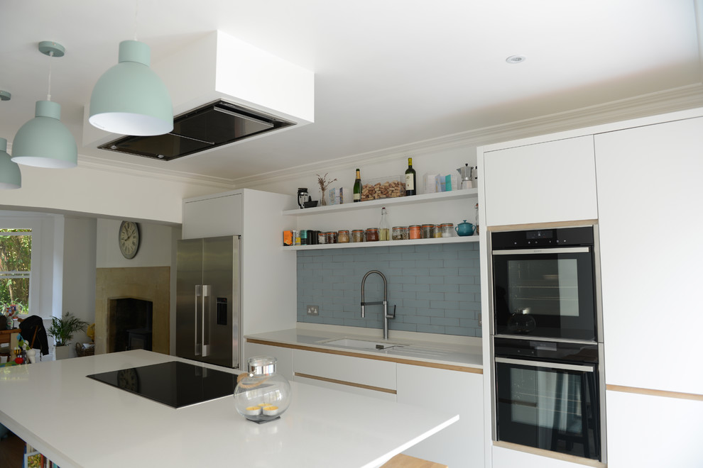 Immagine di una grande cucina minimalista con lavello sottopiano, ante lisce, ante bianche, paraspruzzi blu, paraspruzzi con piastrelle in ceramica e elettrodomestici in acciaio inossidabile