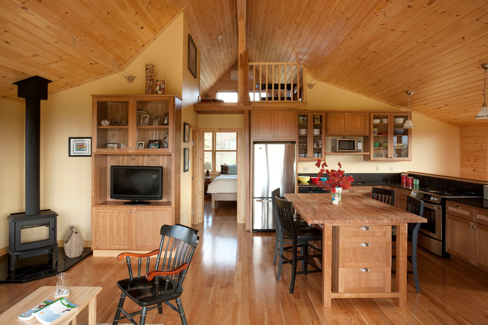 Eat-in kitchen - mid-sized cottage l-shaped light wood floor eat-in kitchen idea in Portland Maine with recessed-panel cabinets, light wood cabinets, wood countertops, black backsplash, stone slab backsplash, an island, an undermount sink and stainless steel appliances
