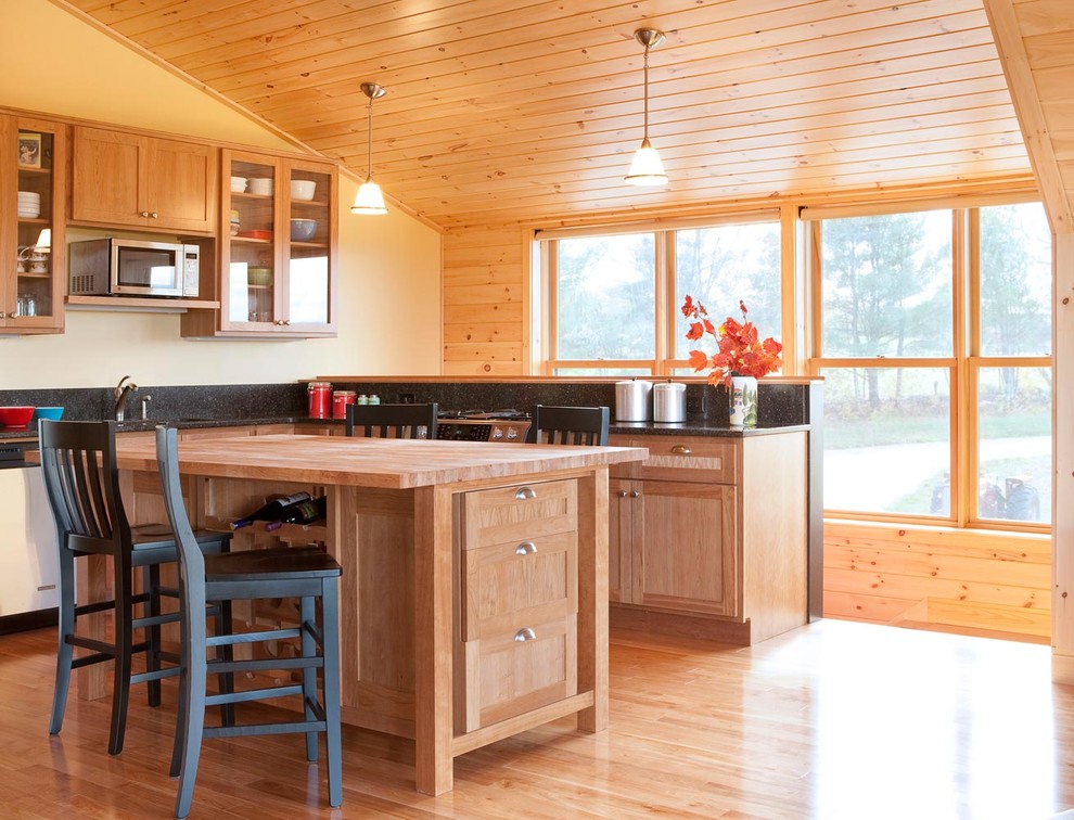 Small country l-shaped light wood floor eat-in kitchen photo in Portland Maine with a double-bowl sink, raised-panel cabinets, light wood cabinets, granite countertops, black backsplash, stone slab backsplash, white appliances and an island