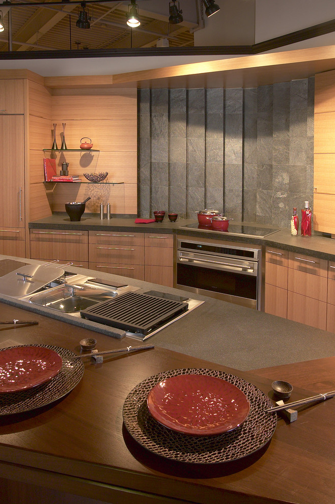 Asiatisk inredning av ett mellanstort kök, med en undermonterad diskho, släta luckor, skåp i ljust trä, bänkskiva i betong, grått stänkskydd, stänkskydd i cementkakel, rostfria vitvaror, linoleumgolv och en köksö