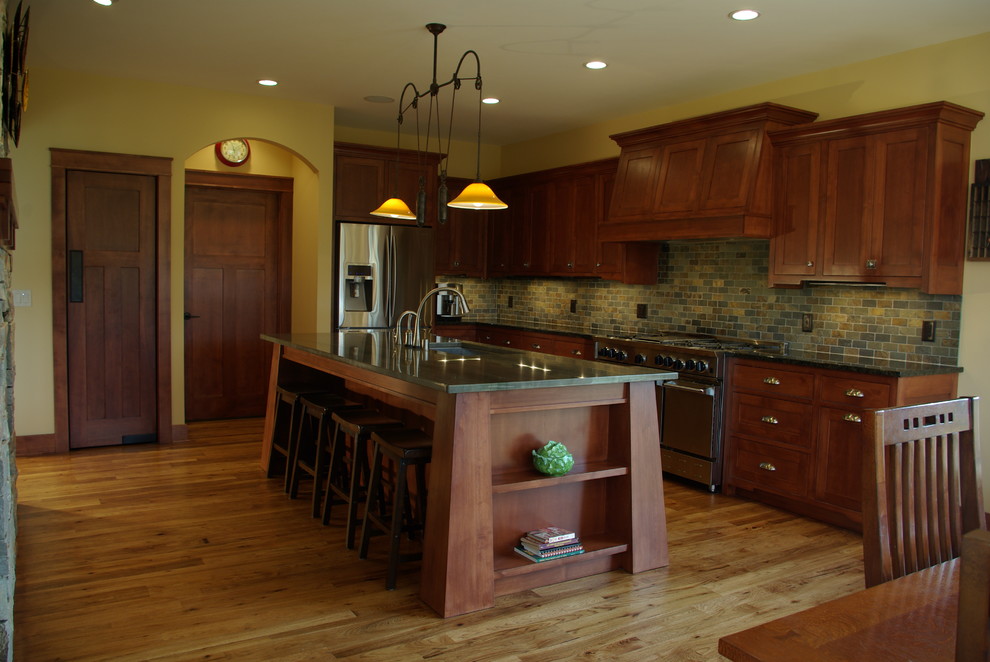 Example of a large arts and crafts l-shaped medium tone wood floor open concept kitchen design in Milwaukee with a single-bowl sink, recessed-panel cabinets, medium tone wood cabinets, stainless steel appliances, an island, granite countertops, beige backsplash and stone tile backsplash