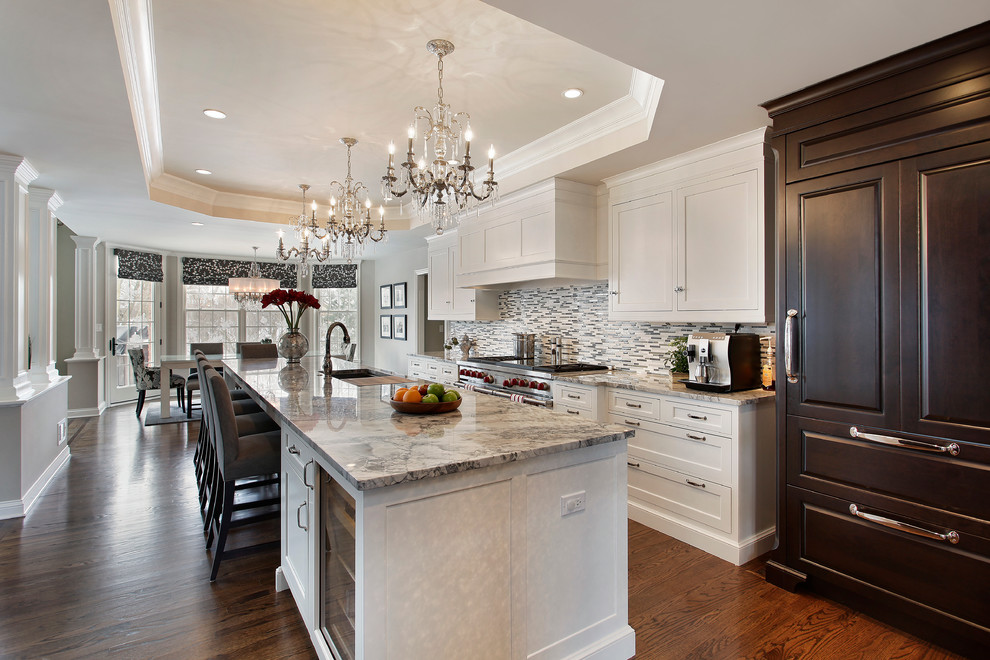 Large elegant l-shaped medium tone wood floor eat-in kitchen photo in Chicago with an undermount sink, recessed-panel cabinets, white cabinets, quartzite countertops, gray backsplash, glass tile backsplash, paneled appliances and an island