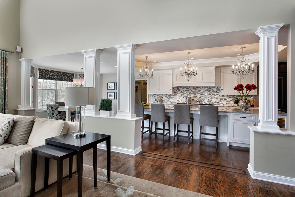 Example of a large classic l-shaped medium tone wood floor eat-in kitchen design in Chicago with an undermount sink, recessed-panel cabinets, white cabinets, quartzite countertops, gray backsplash, glass tile backsplash, paneled appliances and an island
