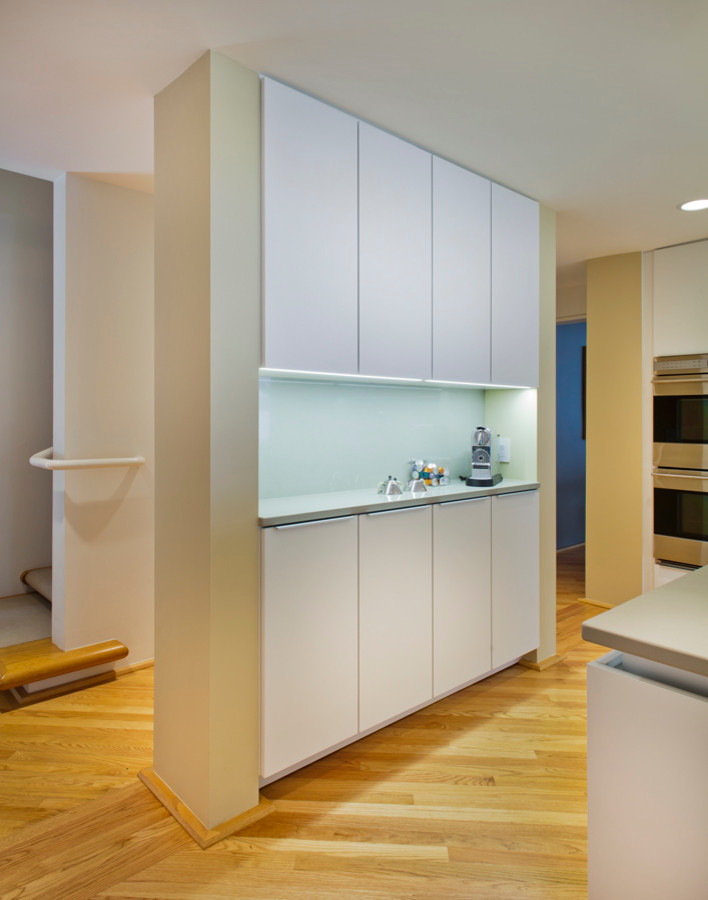 Example of a large trendy u-shaped medium tone wood floor eat-in kitchen design in Minneapolis with an undermount sink, flat-panel cabinets, white cabinets, quartz countertops, white backsplash, glass sheet backsplash, paneled appliances and an island
