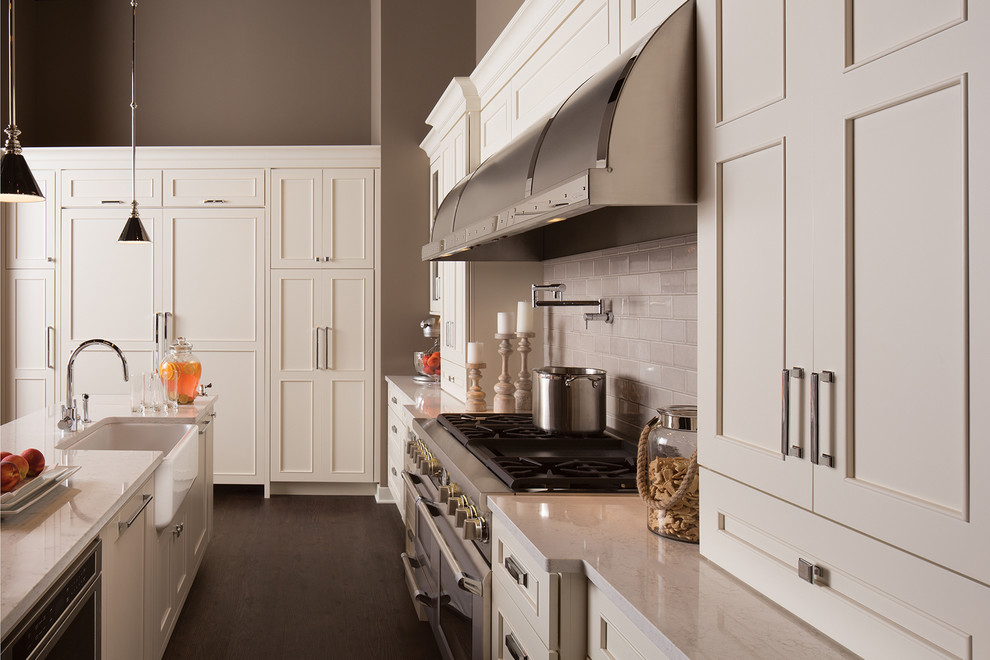 Exempel på ett stort klassiskt vit vitt kök, med en rustik diskho, vita skåp, bänkskiva i kvartsit, vitt stänkskydd, stänkskydd i tunnelbanekakel, rostfria vitvaror, luckor med infälld panel, mörkt trägolv, en köksö och brunt golv