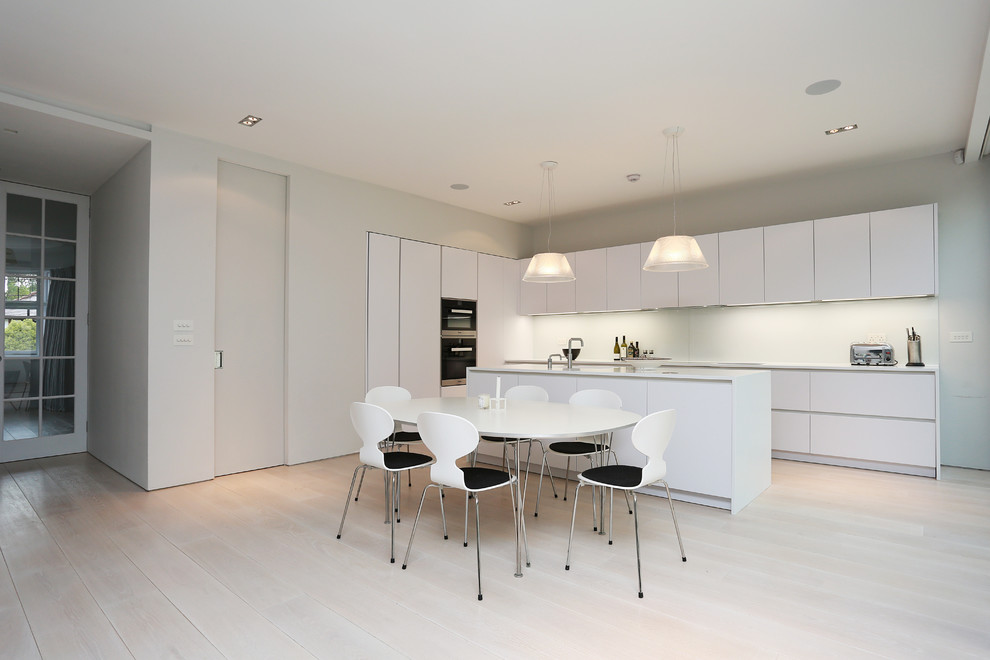 Kitchen - modern single-wall kitchen idea in London with flat-panel cabinets, white cabinets, quartz countertops and an island
