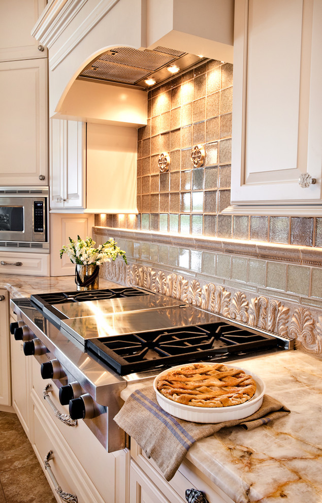 Inspiration for a large timeless u-shaped travertine floor eat-in kitchen remodel in St Louis with a triple-bowl sink, raised-panel cabinets, white cabinets, granite countertops, beige backsplash, stone tile backsplash, paneled appliances and an island