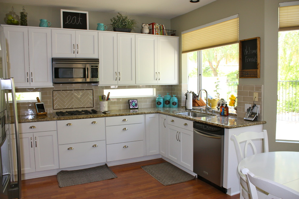 Example of a mid-sized classic u-shaped laminate floor eat-in kitchen design in San Diego with no island, recessed-panel cabinets, white cabinets, granite countertops, beige backsplash, ceramic backsplash, stainless steel appliances and a single-bowl sink