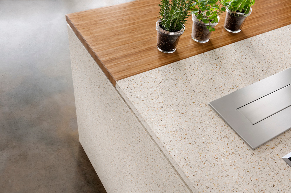 Example of a minimalist eat-in kitchen design in New York with flat-panel cabinets, recycled glass countertops and stainless steel appliances