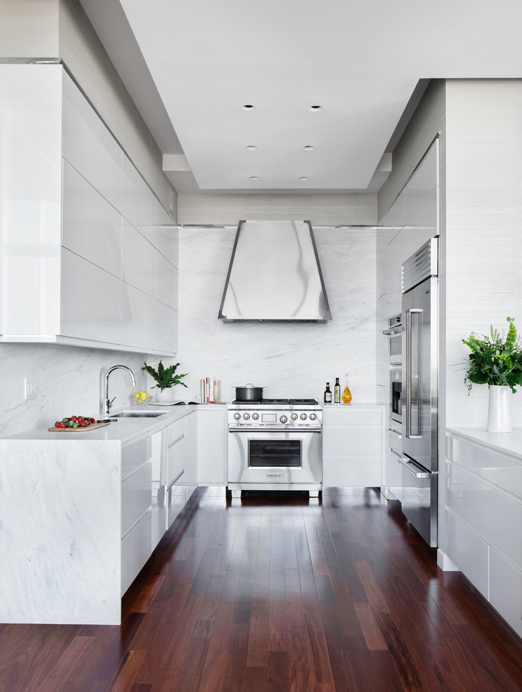 Exempel på ett litet modernt kök, med en undermonterad diskho, släta luckor, vita skåp, marmorbänkskiva, vitt stänkskydd, stänkskydd i marmor, rostfria vitvaror, brunt golv, mellanmörkt trägolv och en halv köksö