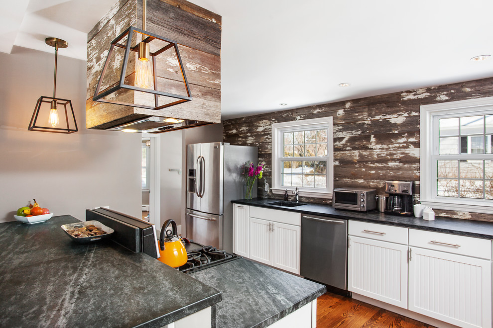 Mid-sized mountain style galley medium tone wood floor eat-in kitchen photo in New York with an undermount sink, beaded inset cabinets, white cabinets, soapstone countertops, brown backsplash, stainless steel appliances and an island