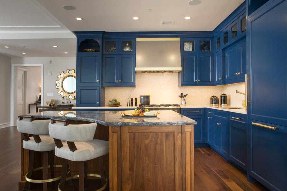 Klassisk inredning av ett mellanstort kök, med en undermonterad diskho, luckor med infälld panel, blå skåp, granitbänkskiva, beige stänkskydd, stänkskydd i stenkakel, svarta vitvaror, mellanmörkt trägolv och en köksö
