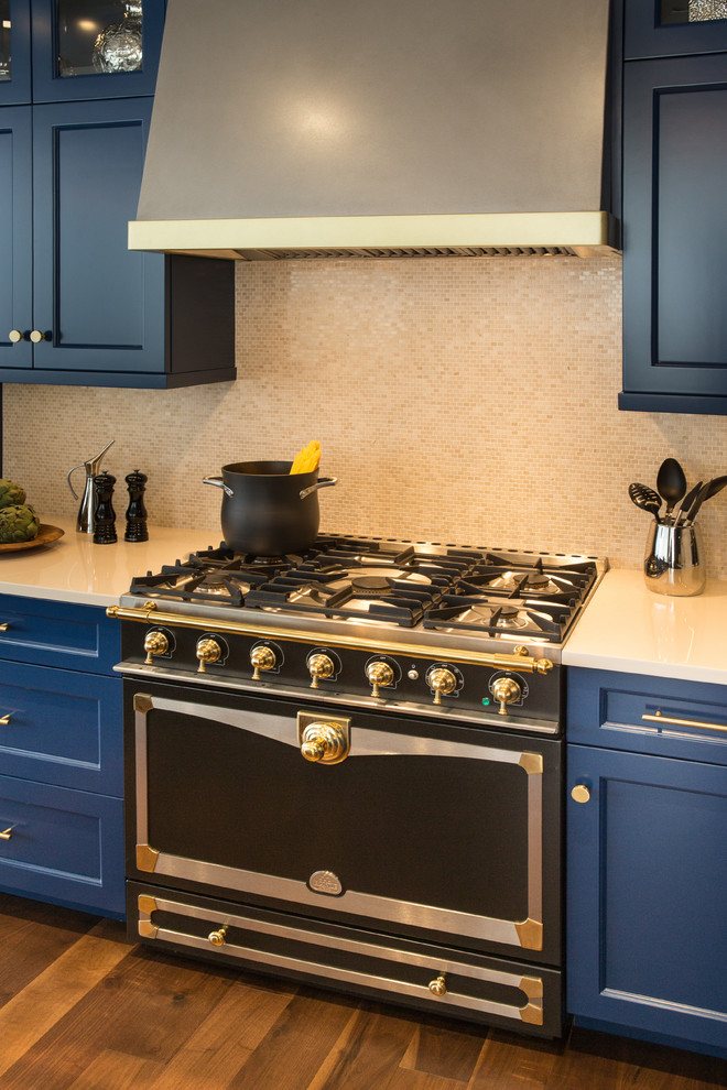 Mid-sized elegant l-shaped medium tone wood floor eat-in kitchen photo in New York with an undermount sink, recessed-panel cabinets, blue cabinets, granite countertops, beige backsplash, stone tile backsplash, black appliances and an island