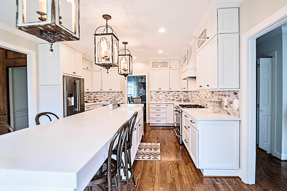 Mid-sized transitional u-shaped medium tone wood floor and brown floor eat-in kitchen photo in Nashville with a farmhouse sink, shaker cabinets, white cabinets, quartz countertops, multicolored backsplash, mosaic tile backsplash, stainless steel appliances, an island and white countertops