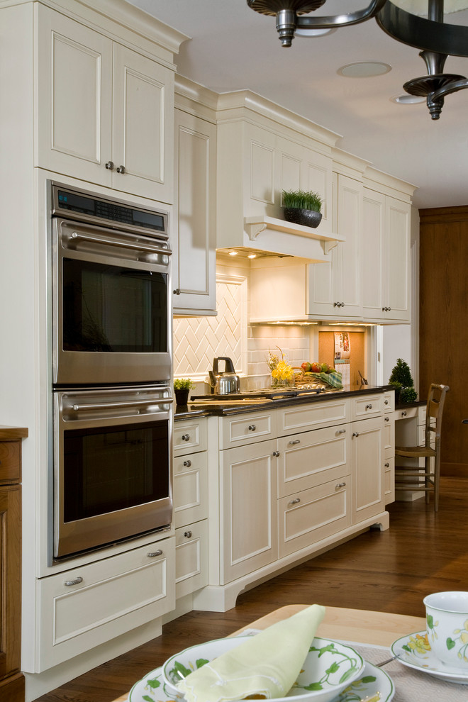 This is an example of a large classic u-shaped enclosed kitchen in Chicago with recessed-panel cabinets, white cabinets, granite worktops, beige splashback, stone tiled splashback, integrated appliances and dark hardwood flooring.