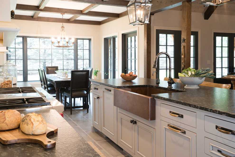 Bild på ett mellanstort rustikt kök, med en rustik diskho, släta luckor, vita skåp, bänkskiva i täljsten, vitt stänkskydd, stänkskydd i marmor, integrerade vitvaror, klinkergolv i porslin, en köksö och grått golv