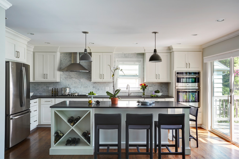 Foto på ett mellanstort vintage grå l-kök, med skåp i shakerstil, vita skåp, bänkskiva i kvartsit, grått stänkskydd, rostfria vitvaror, mörkt trägolv, en köksö, en undermonterad diskho och brunt golv
