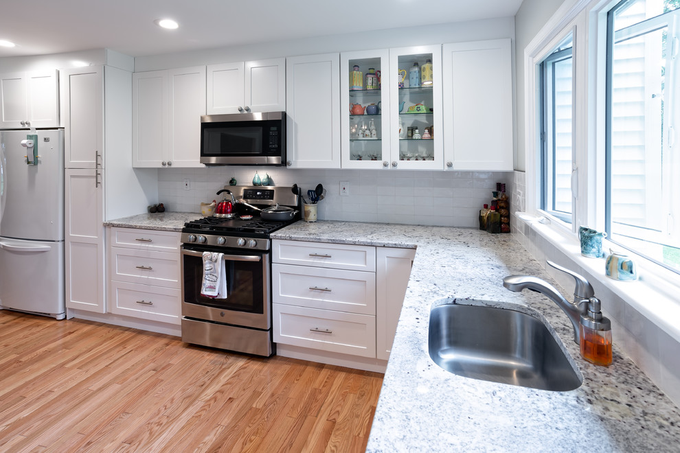 Inspiration for a mid-sized transitional u-shaped light wood floor and brown floor eat-in kitchen remodel in Philadelphia with an undermount sink, shaker cabinets, white cabinets, granite countertops, white backsplash, subway tile backsplash, stainless steel appliances, no island and yellow countertops