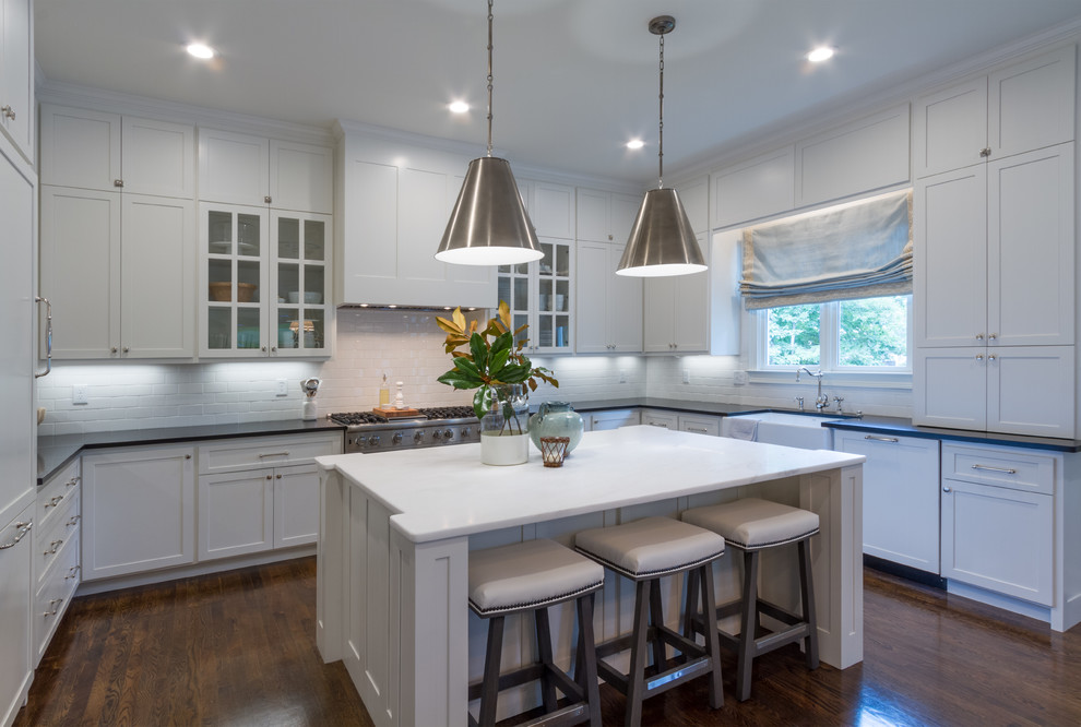 Example of a large minimalist u-shaped dark wood floor and brown floor eat-in kitchen design in Atlanta with a drop-in sink, shaker cabinets, white cabinets, granite countertops, white backsplash, ceramic backsplash, stainless steel appliances and an island