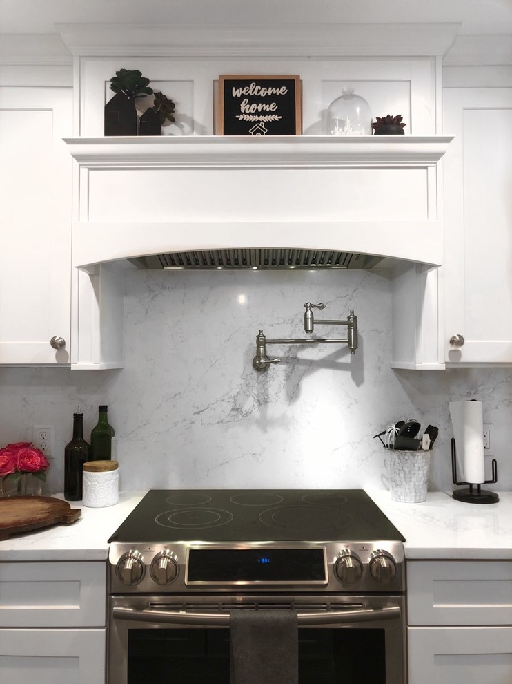 Foto di un cucina con isola centrale minimal con lavello stile country, ante in stile shaker, ante bianche, elettrodomestici in acciaio inossidabile e top bianco