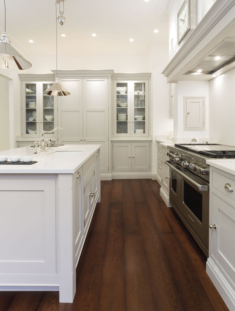 Inspiration for a large contemporary l-shaped kitchen/diner in London with shaker cabinets, white cabinets, white splashback, stainless steel appliances, dark hardwood flooring, an island and brown floors.