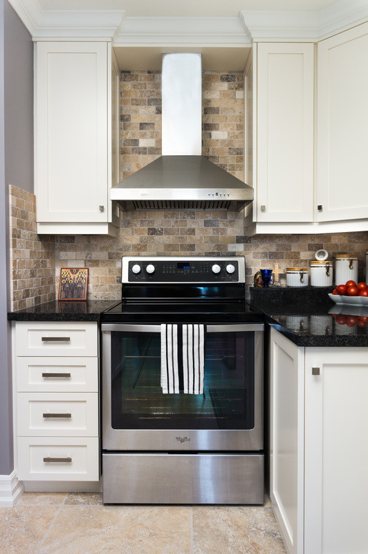 Photo of a large classic u-shaped enclosed kitchen in Toronto with a submerged sink, shaker cabinets, white cabinets, stainless steel appliances, a breakfast bar, granite worktops, beige splashback, ceramic flooring and brick splashback.