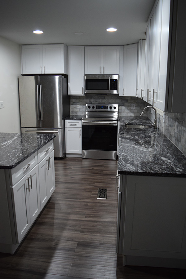 Mid-sized transitional l-shaped laminate floor and gray floor eat-in kitchen photo in DC Metro with an undermount sink, shaker cabinets, white cabinets, granite countertops, white backsplash, subway tile backsplash, stainless steel appliances and an island