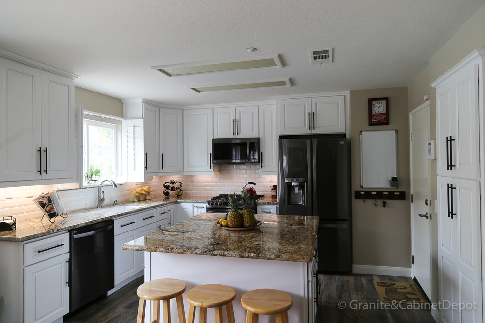 Exempel på ett mellanstort modernt flerfärgad flerfärgat kök, med en undermonterad diskho, luckor med upphöjd panel, vita skåp, granitbänkskiva, vitt stänkskydd, stänkskydd i tunnelbanekakel, rostfria vitvaror, mellanmörkt trägolv och en köksö