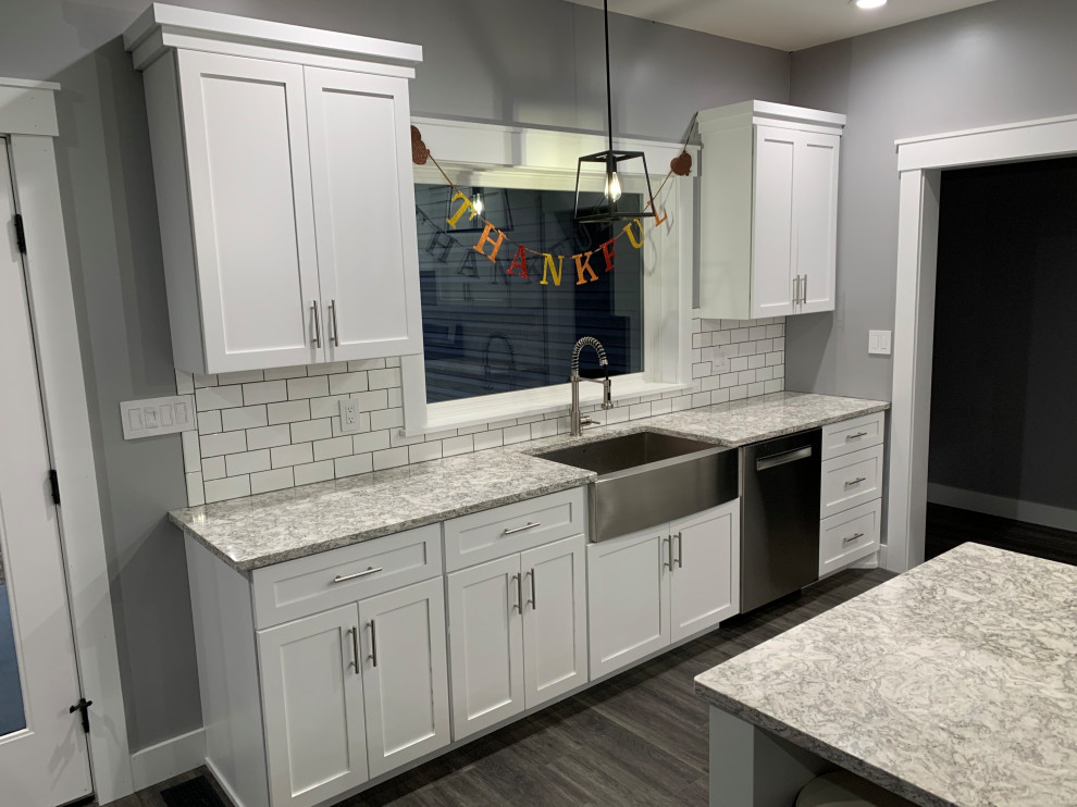 Foto på ett mellanstort amerikanskt grå kök, med en rustik diskho, skåp i shakerstil, vita skåp, bänkskiva i kvarts, vitt stänkskydd, stänkskydd i keramik, rostfria vitvaror, vinylgolv, en köksö och grått golv