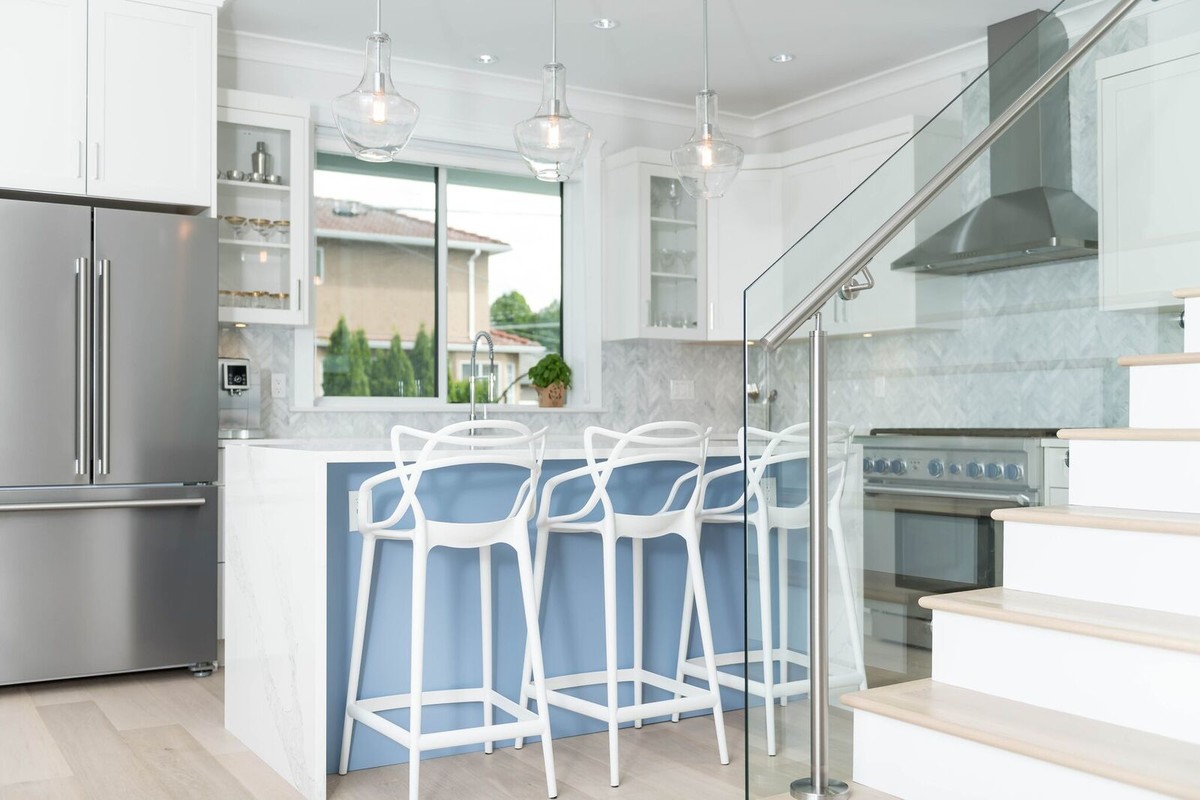 Open concept kitchen - mid-sized transitional u-shaped light wood floor open concept kitchen idea in Vancouver with a farmhouse sink, shaker cabinets, white cabinets, marble countertops, white backsplash, subway tile backsplash, stainless steel appliances and an island