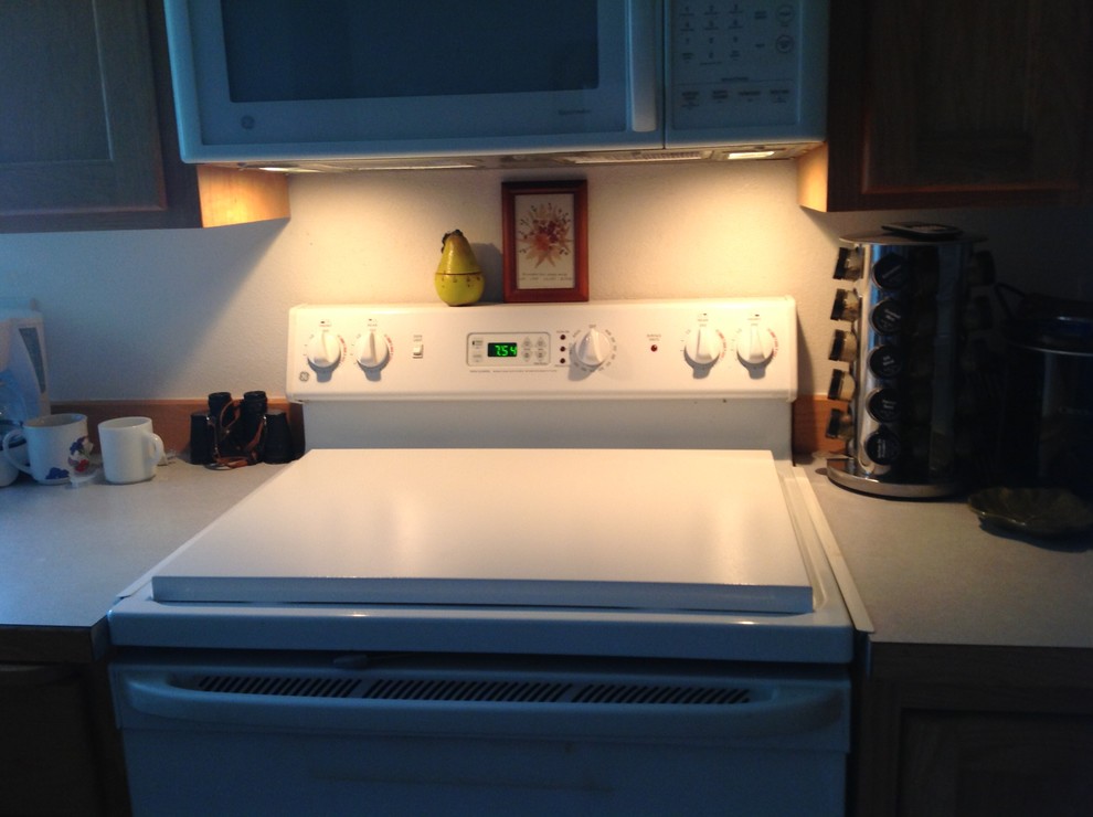 Cette image montre une petite cuisine américaine minimaliste avec un électroménager blanc.