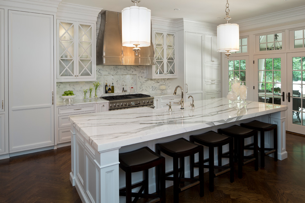 Inspiration for a large traditional l-shaped kitchen in Indianapolis with a belfast sink, beaded cabinets, white cabinets, white splashback, stone tiled splashback, integrated appliances, dark hardwood flooring and an island.