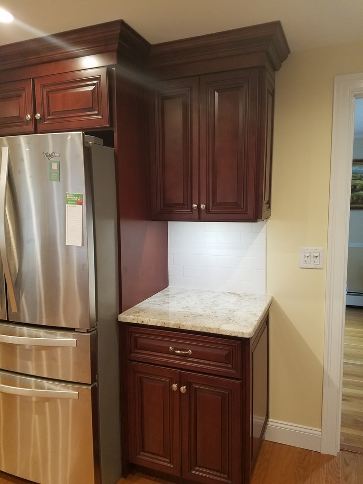 Inspiration for a mid-sized timeless l-shaped light wood floor and brown floor enclosed kitchen remodel in Providence with a double-bowl sink, raised-panel cabinets, dark wood cabinets, granite countertops, white backsplash, subway tile backsplash, stainless steel appliances, no island and gray countertops