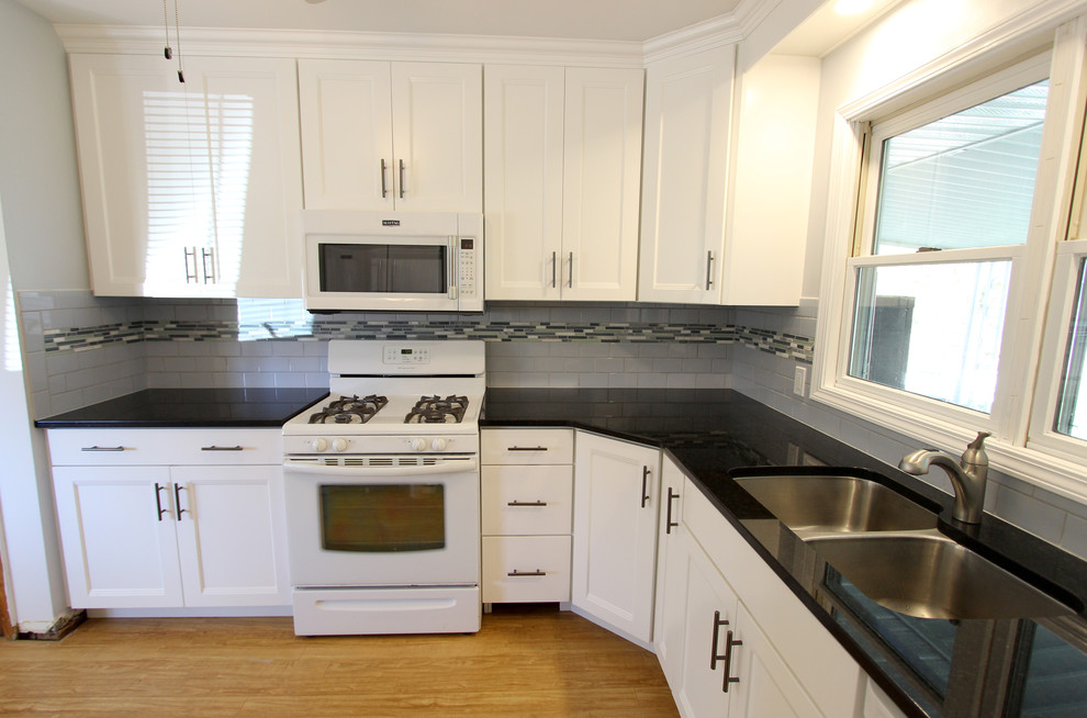 Exempel på ett litet klassiskt kök, med en undermonterad diskho, släta luckor, vita skåp, granitbänkskiva, blått stänkskydd, stänkskydd i tunnelbanekakel och vita vitvaror
