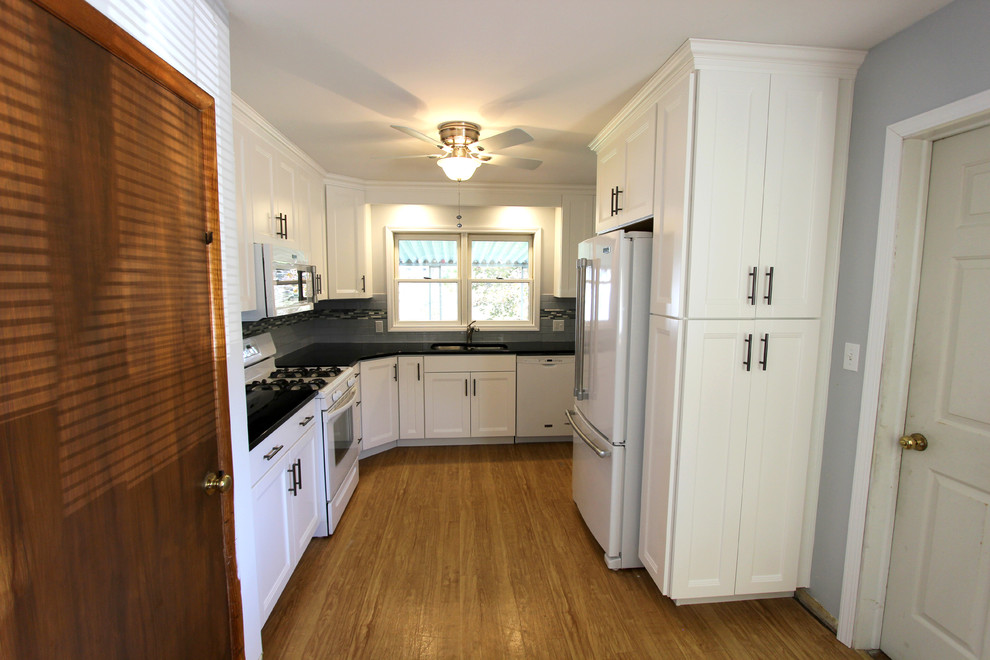 This is an example of a small traditional u-shaped kitchen/diner in Cleveland with a submerged sink, flat-panel cabinets, white cabinets, granite worktops, blue splashback, metro tiled splashback, white appliances and no island.