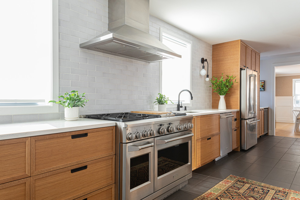 Foto de cocina lineal moderna grande abierta con puertas de armario verdes, salpicadero blanco, salpicadero de ladrillos, electrodomésticos de acero inoxidable, una isla, suelo gris y encimeras blancas