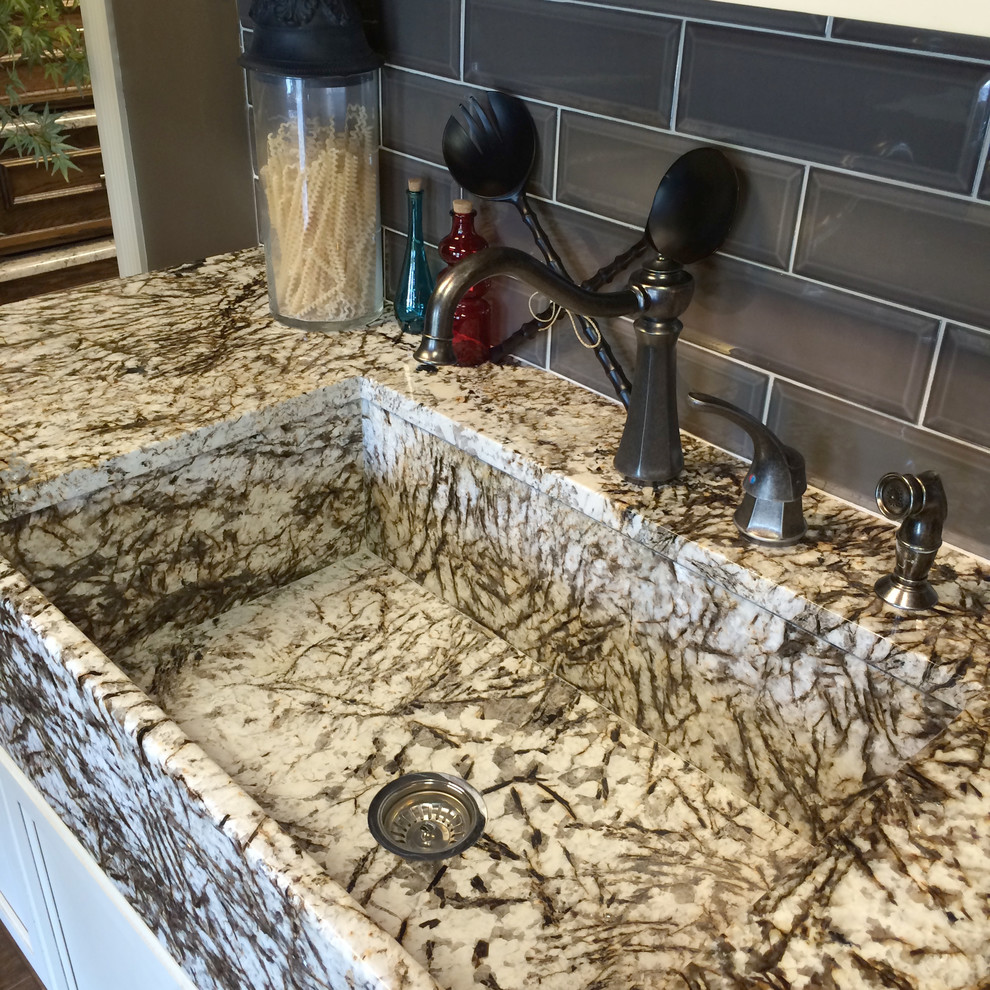 Bild på ett mellanstort lantligt kök, med en rustik diskho, skåp i shakerstil, vita skåp, granitbänkskiva, grått stänkskydd, stänkskydd i keramik, mörkt trägolv och en köksö
