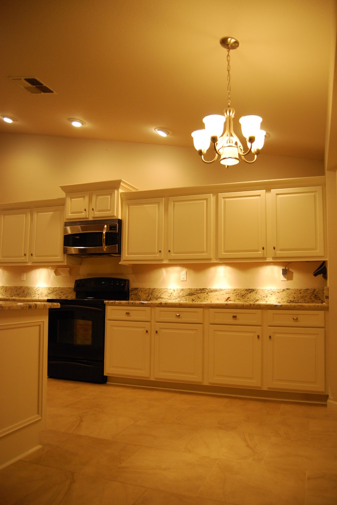 Inredning av ett klassiskt mellanstort kök, med en undermonterad diskho, luckor med upphöjd panel, vita skåp, granitbänkskiva, stänkskydd i sten, rostfria vitvaror, klinkergolv i porslin, en köksö och beiget golv