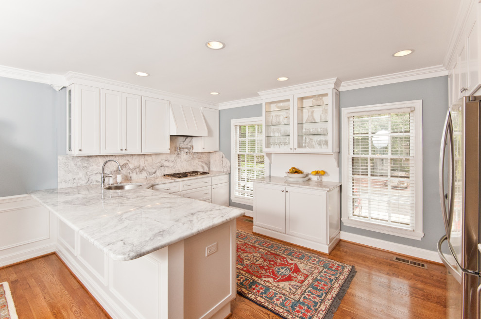 Photo of a medium sized traditional l-shaped kitchen in DC Metro with a submerged sink, shaker cabinets, white cabinets, white splashback, stainless steel appliances, medium hardwood flooring, brown floors, white worktops and quartz worktops.