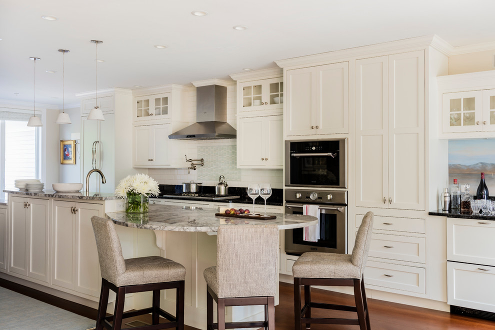 Klassische Küchenbar mit Schrankfronten im Shaker-Stil, weißen Schränken, Küchengeräten aus Edelstahl, braunem Holzboden und Kücheninsel in Boston