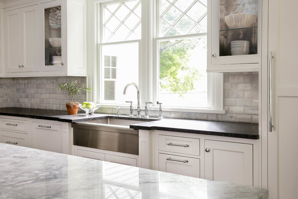 Large transitional l-shaped dark wood floor enclosed kitchen photo in New York with a farmhouse sink, recessed-panel cabinets, white cabinets, quartzite countertops, gray backsplash, stone tile backsplash, paneled appliances and an island