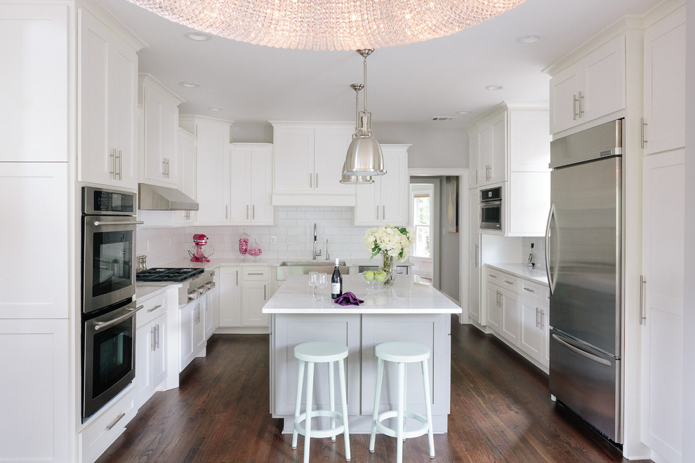Inspiration for a classic u-shaped enclosed kitchen in Atlanta with a belfast sink, shaker cabinets, white cabinets, white splashback, stainless steel appliances, dark hardwood flooring and an island.