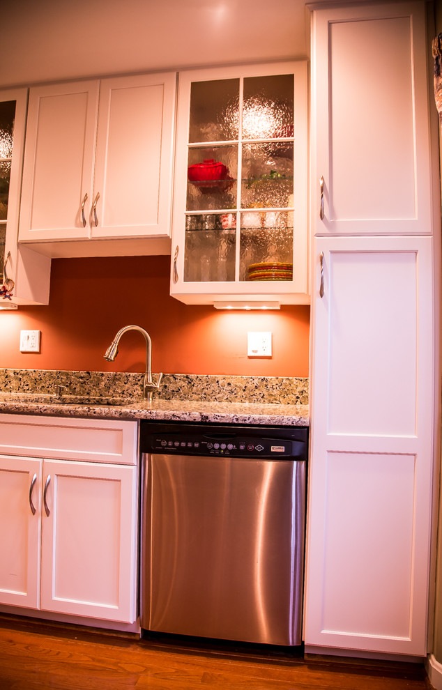 Exemple d'une cuisine chic en L avec un évier encastré, un placard à porte shaker, des portes de placard blanches, une crédence rouge, un électroménager en acier inoxydable, un sol en bois brun et aucun îlot.