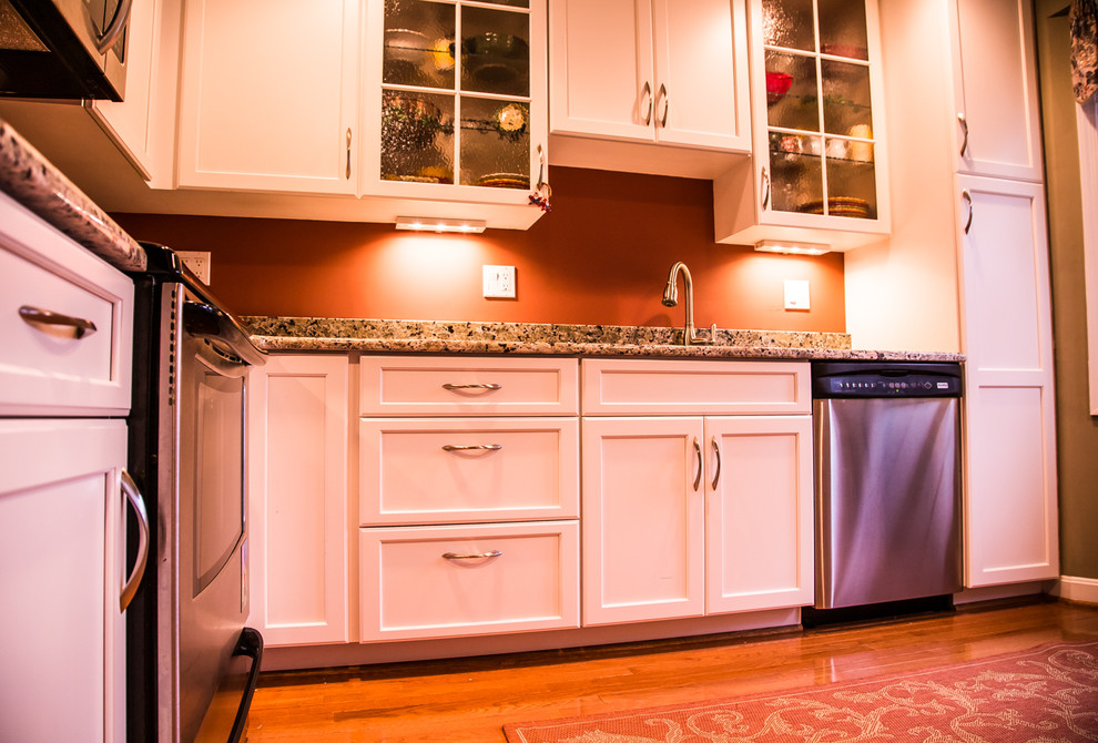 Bild på ett vintage l-kök, med en undermonterad diskho, skåp i shakerstil, vita skåp, rött stänkskydd, rostfria vitvaror och mellanmörkt trägolv